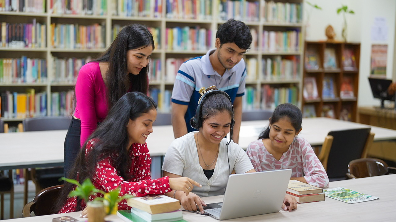 Group of students working on a laptop in a library